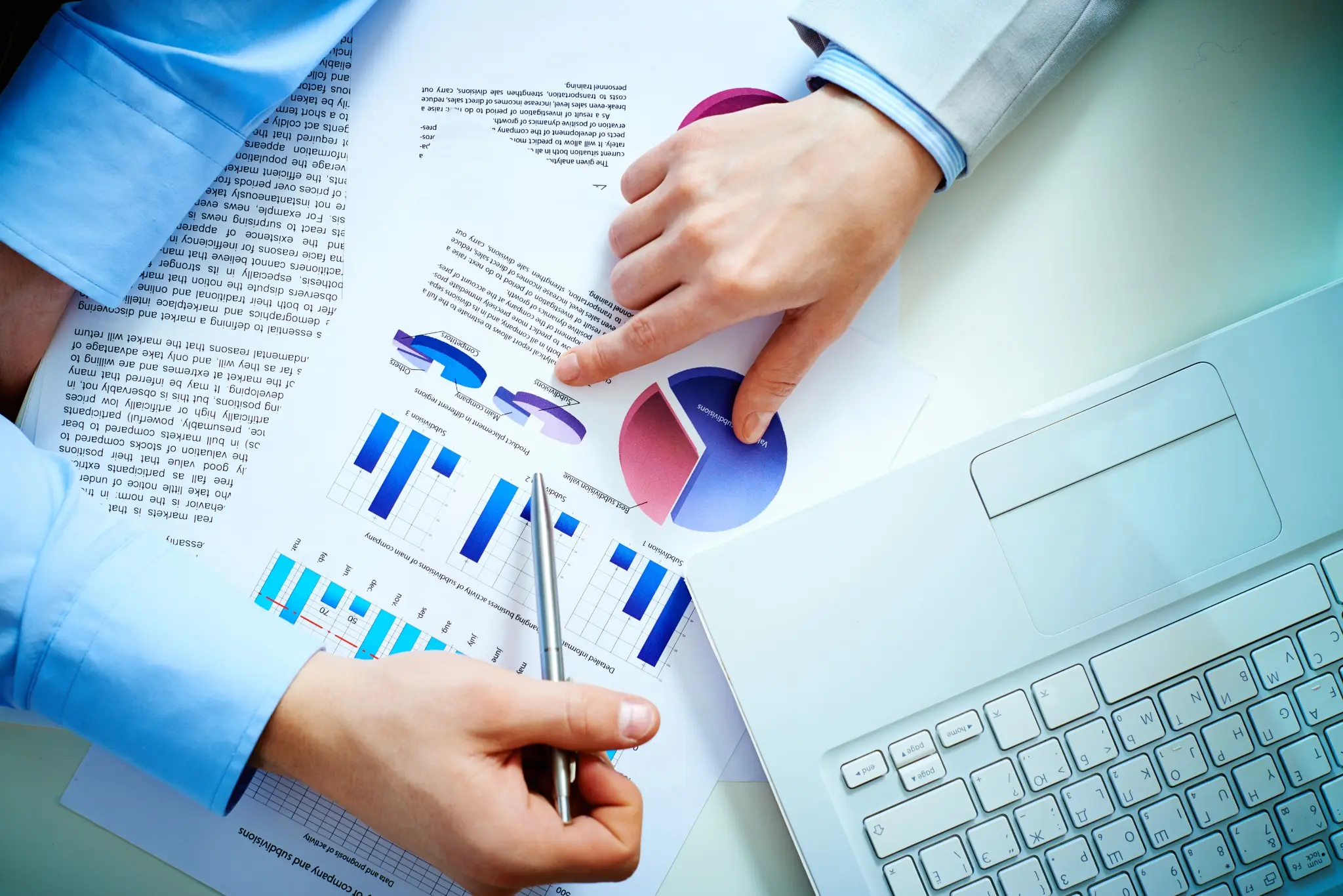 Market professional analysing financial charts and portfolio data beside a laptop